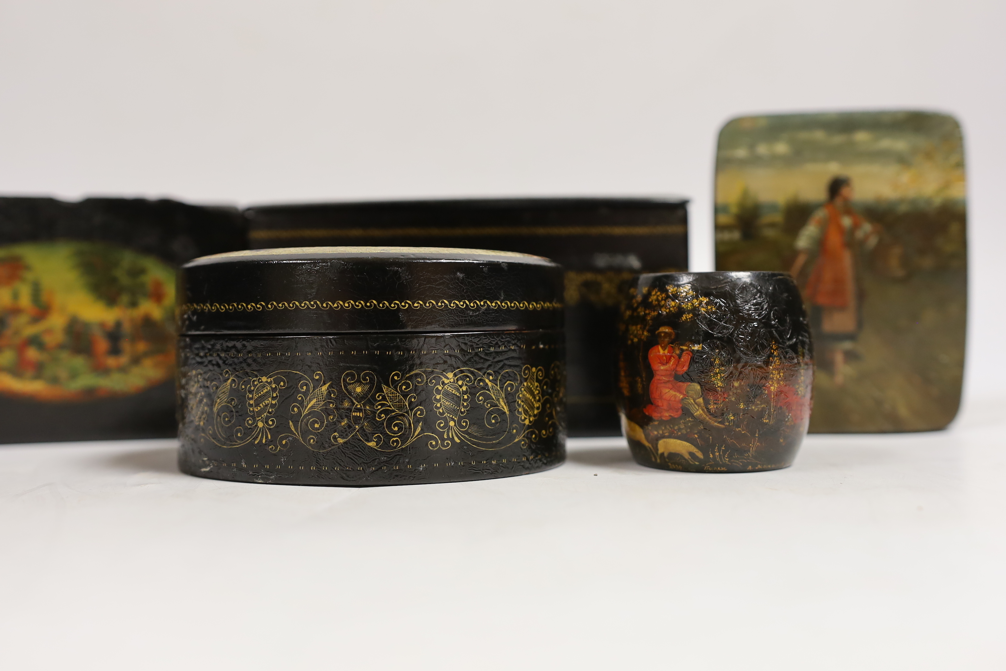 Four Russian lacquer boxes and a similar napkin ring, Palekh and others, the oval box painted with figures from legend and the others with rural scenes, some inscribed with the subject or artist, largest 13.7cm wide (5)